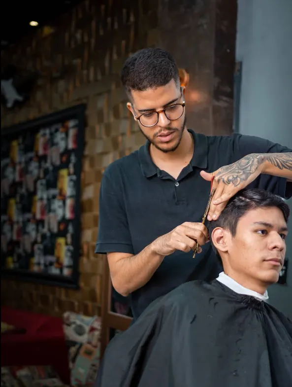 Barbeiro cortando o cabelo de um cliente na tesoura